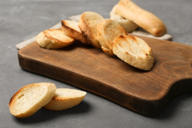 Houten bord met geroosterd brood op grijze achtergrond