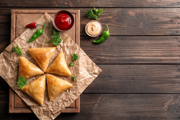 Houten bord met heerlijke samosa's op tafel