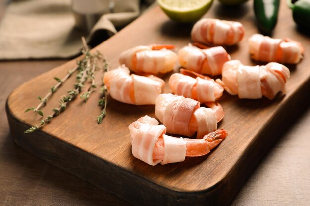 Houten bord met in spek gewikkelde garnalen op tafel close-up