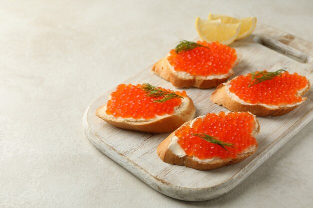 Houten bord met sandwiches met rode kaviaar op witte gestructureerde achtergrond