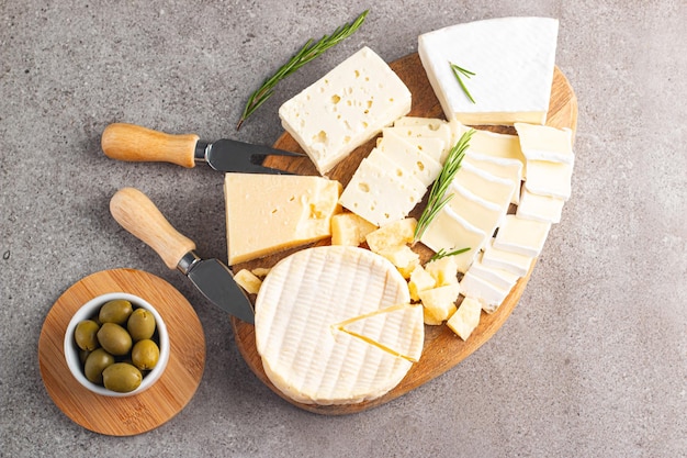 Houten bord met verschillende kazen en olijven Brie Camembert Parmesan feta blauwe kaas Italiaans