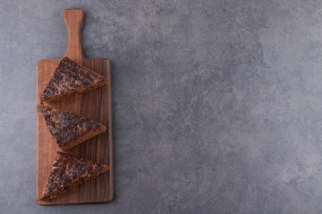 Houten bord van zoete gesneden koek op stenen tafel.