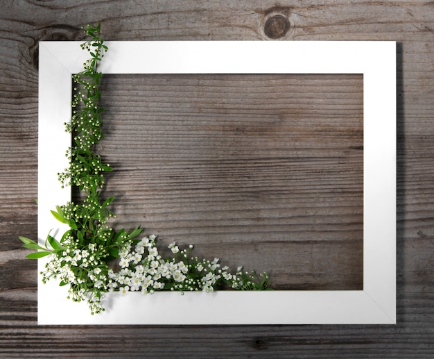 Houten bruine achtergrond. Wit frame met bloemen spirea. Feestelijk frame. Kopieer ruimte, plat lag.