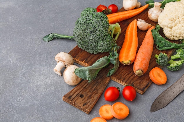 Houten bureau met verse groenten, gezond eten koken op grijze achtergrond, kopieer ruimte.