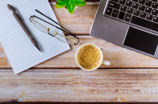 Houten bureaulijst met laptop computer en hoofdtelefoons glazen pen