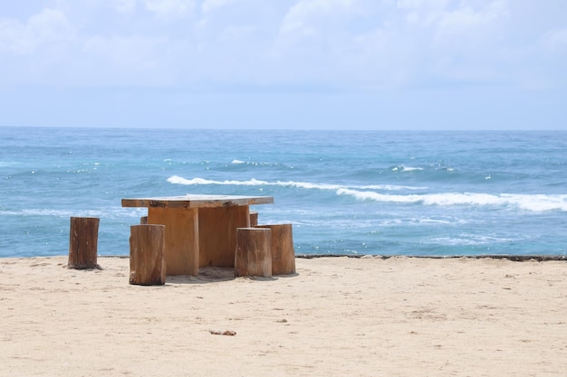 Houten cafétafel en stoelen op een tropisch strand met blauwe zee op de achtergrond