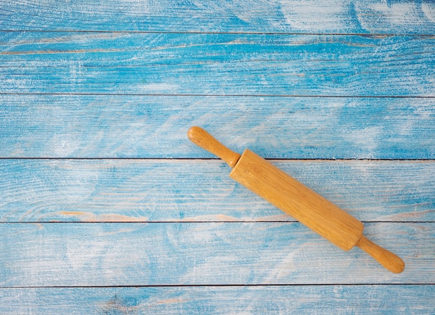 Houten deegrol op blauwe houten tafel.