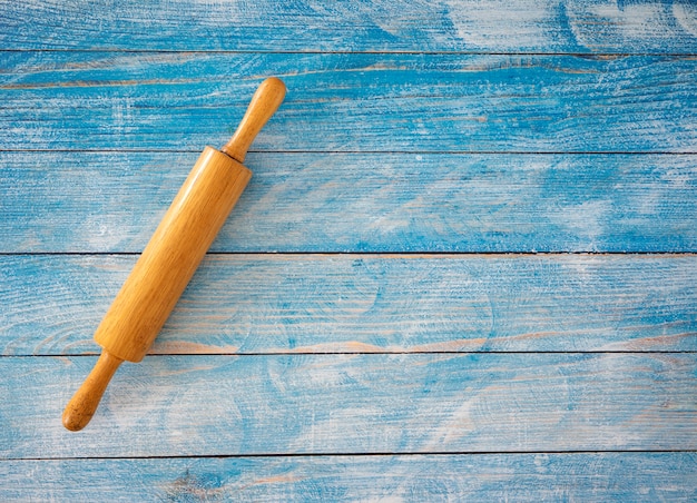 Houten deegrol op blauwe houten tafel.