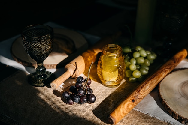 Houten deegroller, druiven, glas en een kaars op een tafel in het zonlicht