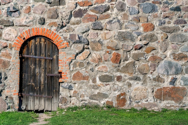 Houten deur in een muur van ongelijke stenen vintage gebouw achtergrond