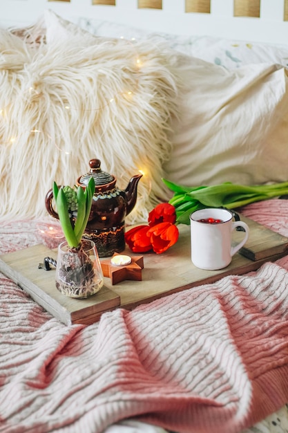 Houten dienblad met thee en lentebloemen op een gezellig bed, verticale foto. Ontbijt concept. Hoge kwaliteit foto
