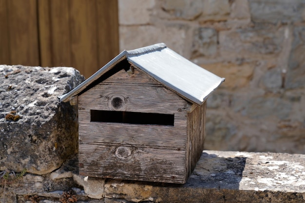 Houten donkergrijze klassieke brievenbus natuurlijk op oude oude stenen muuromheining buiten straat