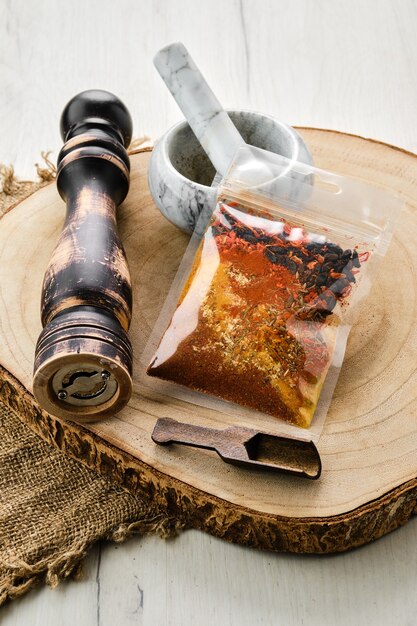 Houten doorsnede met een setje kruiden voor pilaf in plastic verpakking en stenen vijzel en molen