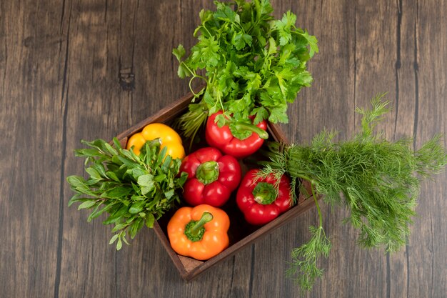 Houten doos met kleurrijke paprika's en Groenen op houten oppervlak