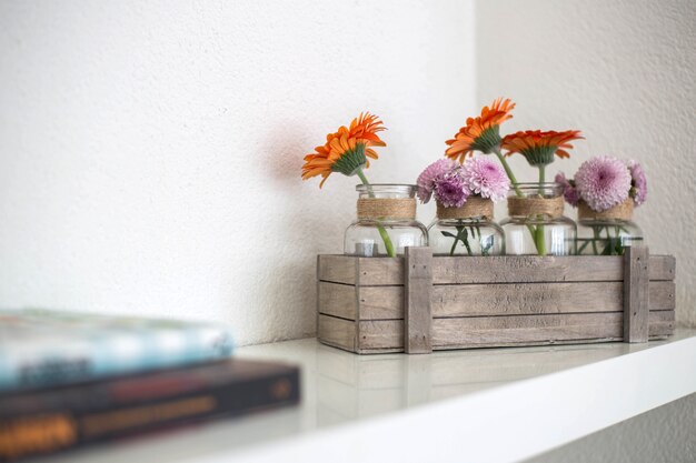 Houten doos met oranje en roze bloemen op witte plank