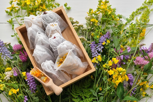 Houten doos met theezakjes gevuld met droge geneeskrachtige kruiden Stelletje geneeskrachtige planten op tafel Bovenaanzicht