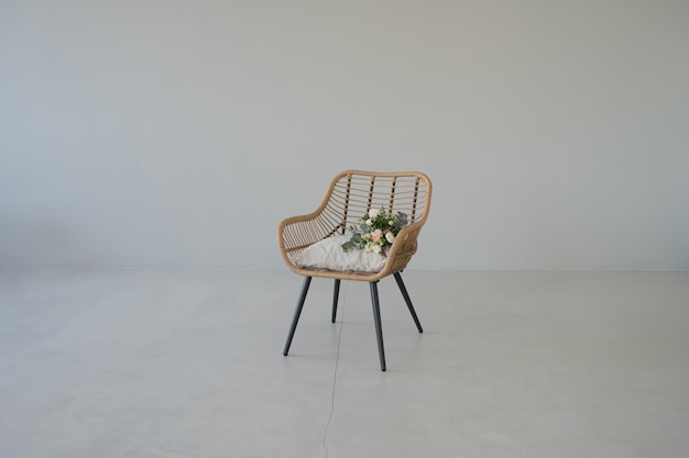 Houten fauteuil met bloemen op de achtergrond van een lege witte muur