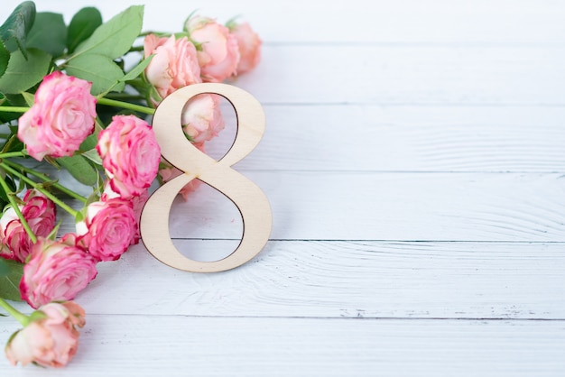 Houten figuur 8 met roze bloemen op een witte tafel. internationale vrouwendag. 8 maart