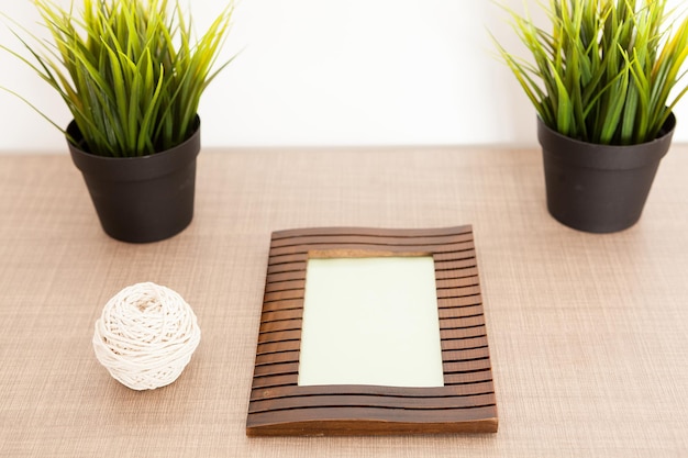 Houten fotolijst op tafel naast potten gras