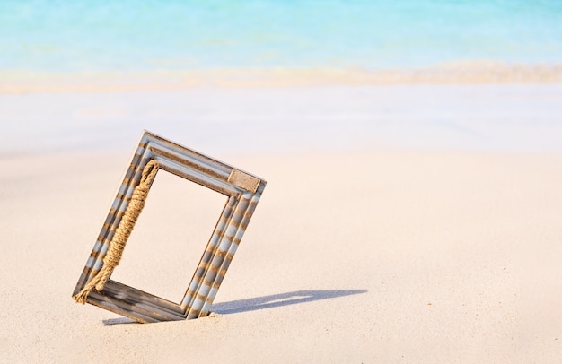 Houten fotolijstjes op het tropische zeezand en de strandachtergrond met kopieerruimte