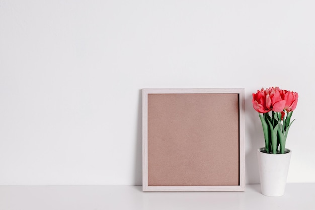 Houten frame leunend op witte muur in licht interieur met kunstmatige plant Bespotten met kopieerruimte