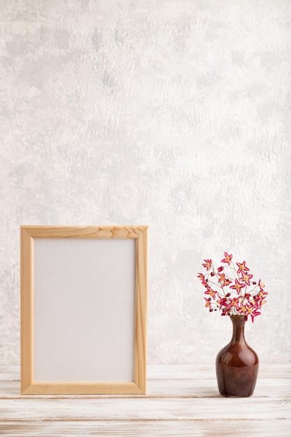 Houten frame met paarse barrenwort bloemen in keramische vaas op grijze betonnen achtergrond zijaanzicht kopie ruimte mockup