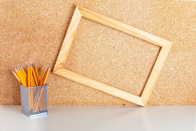 Houten frame op prikbord en potloden in houder