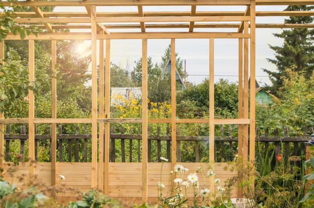 Houten frameconstructie van een nieuwe veranda of tuinhuisje op het grondgebied van een landperceel, in de zomer, buiten.