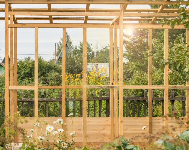 Houten frameconstructie van een nieuwe veranda of tuinhuisje op het grondgebied van een landperceel, in de zomer, buiten.