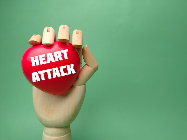 Houten hand met rood hart met het woord HEART ATTACK op een groene achtergrond