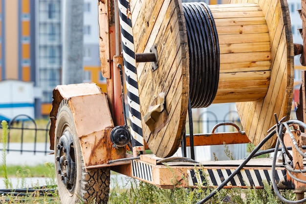 Houten haspel met hoogspanningskabel gemonteerd op een aanhanger voor eenvoudig transport en opbergen hoogspanningskabel in de grond leggen kabels leggen van ondergrondse communicatie