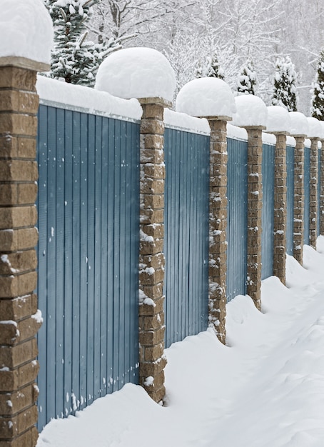 Houten hek met sneeuw bedekte stenen zuilen