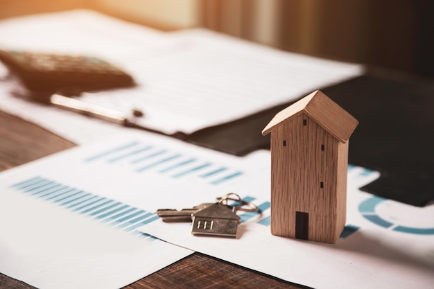 Houten huis met huissleutels op bureau met bankleningdocumenten