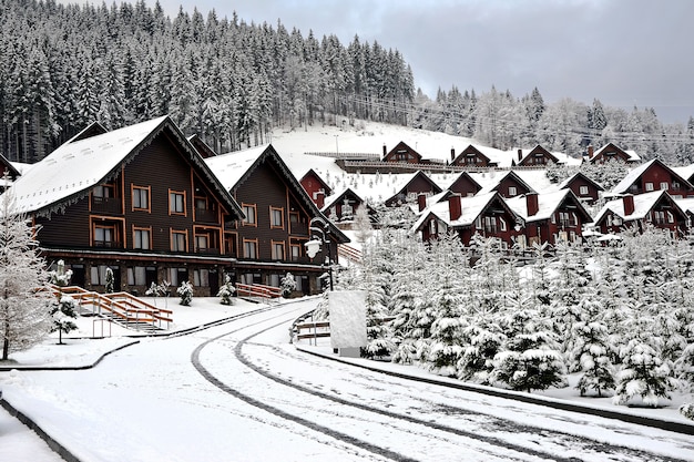 Houten huisjes vakantiehuis in vakantieoord in de bergen bedekt met verse sneeuw in de winter. Winterstraat na sneeuwval.