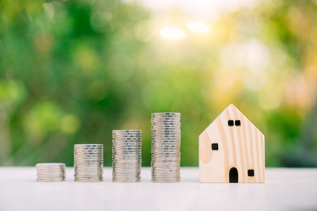 Houten huismodel en rij van muntstukgeld op aardachtergrond