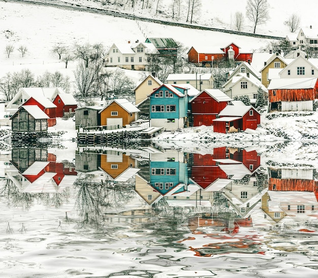 Foto houten huizen aan de oevers van de noorse fjord met reflectie in het water