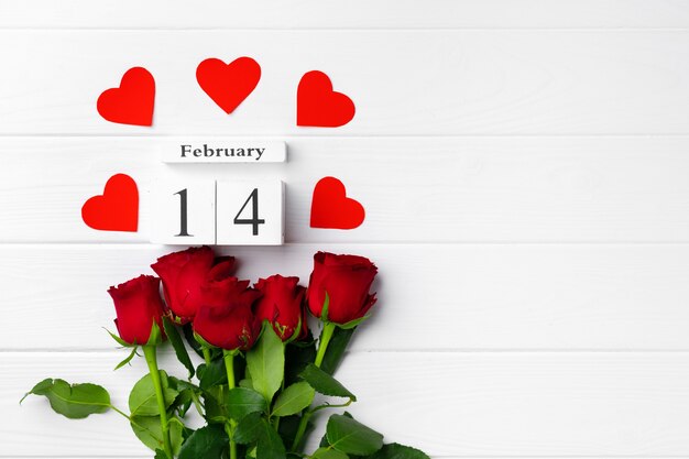 Houten kalender 14 februari en rozen op witte achtergrond plat leggen