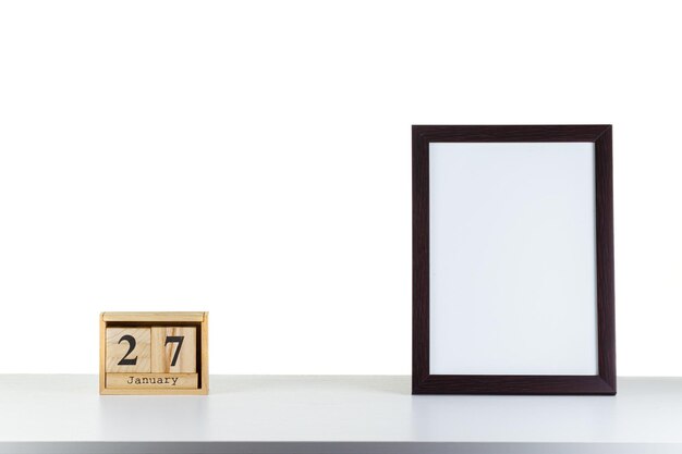 Houten kalender 27 januari met frame voor foto op witte tafel en achtergrond