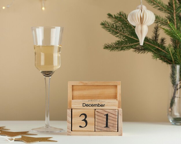 Houten kalender december nieuwjaarsachtergrond een glas wijn een boomtak een slinger minimalisme