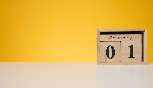 Houten kalender gemaakt van kubussen op een gele achtergrond Datum 1 januari begin van het jaar