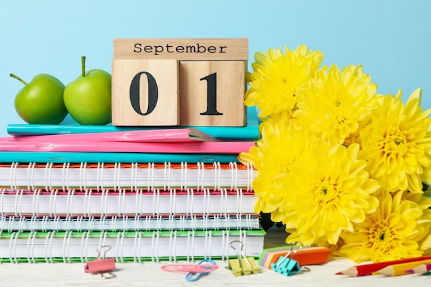 Houten kalender met 1 september en schoolspullen op blauw