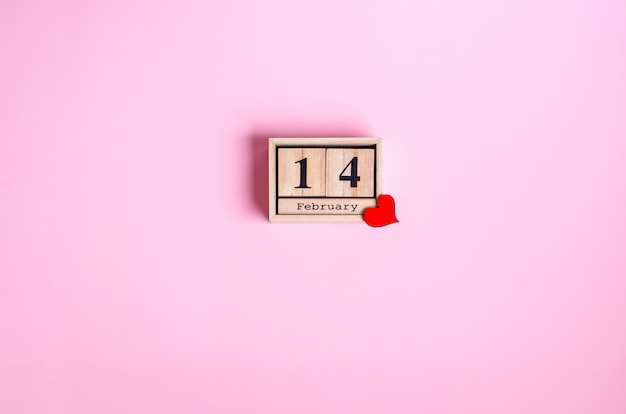 Foto houten kalender met datum 14 februari en rood hart tot valentijnsdag op roze