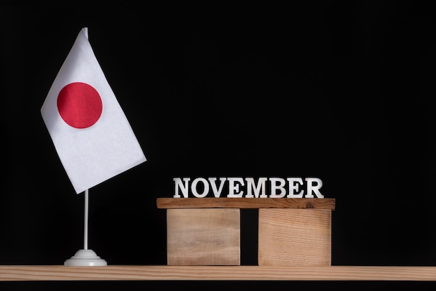 Houten kalender van november met Japanse vlag op zwarte achtergrond Datums van Japan in november