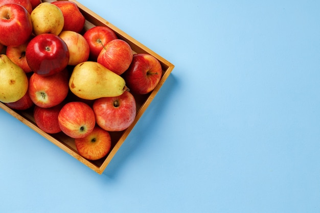 Houten kist met appels en peren op blauwe achtergrond