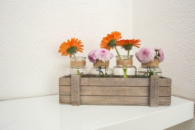 Houten kist met oranje en roze bloemen op witte plank, witte achtergrond, modern design. woonkamer