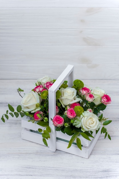 Houten kist met witte en roze rozen en chrysanten op wit houten bord. Decoratie van huis. Bloemen dozen. Bruiloft decoratie