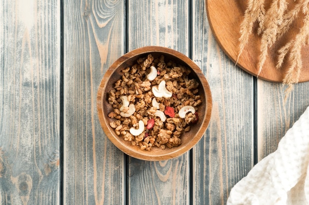 Houten kom gevuld met volkoren muesli met bessen en noten Dienblad met aartjes en witte handdoek op rustiek oppervlak