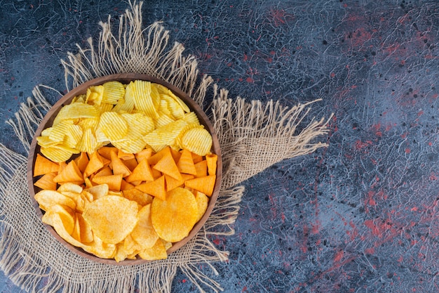 Houten kom met snacks voor bier op een donkere achtergrond.