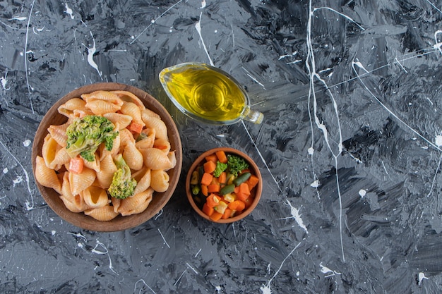 Houten kom smakelijke zeeschelppasta met frisse salade op marmeren oppervlak.