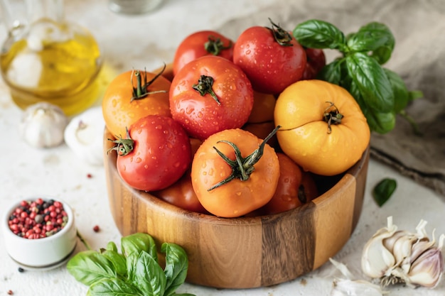 Houten kom verse kleurrijke tomaten knoflook basilicum peper en olijfolie op gestructureerde achtergrond